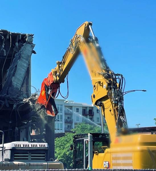 excavator with cutter attachment scraping building